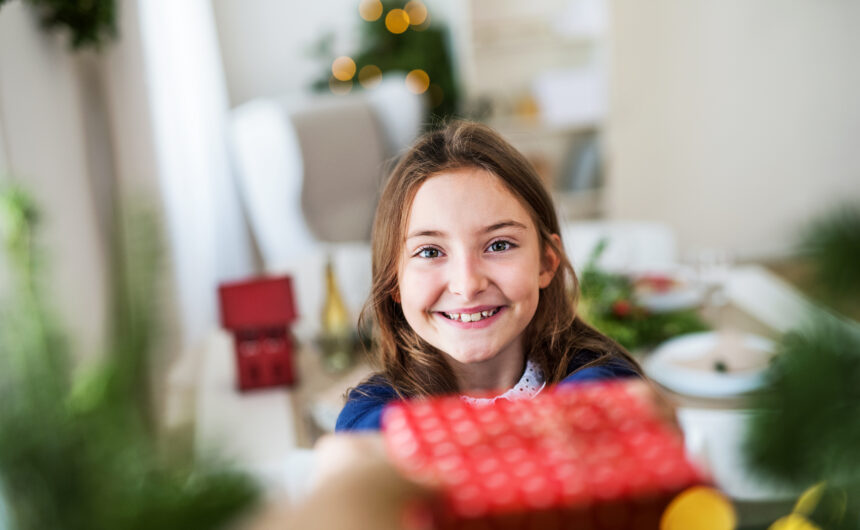 A small girl with a present at home at Christmas time. Presentes de Natal 2023